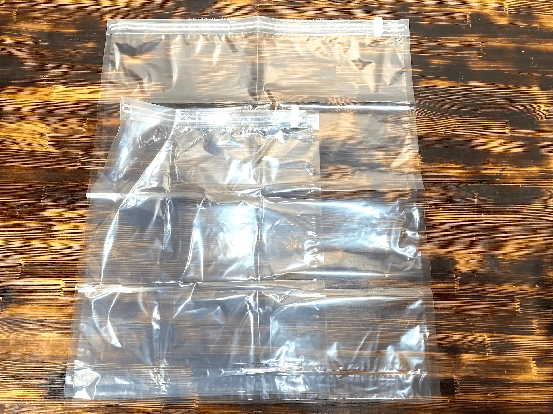 ダイソーのトラベル用衣類圧縮袋LとMを重ねて比較した物