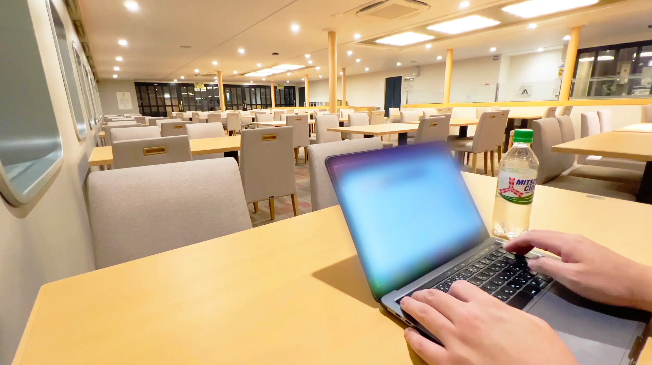 名門大洋フェリーきょうと夜の展望レストランの店内でパソコン作業風景