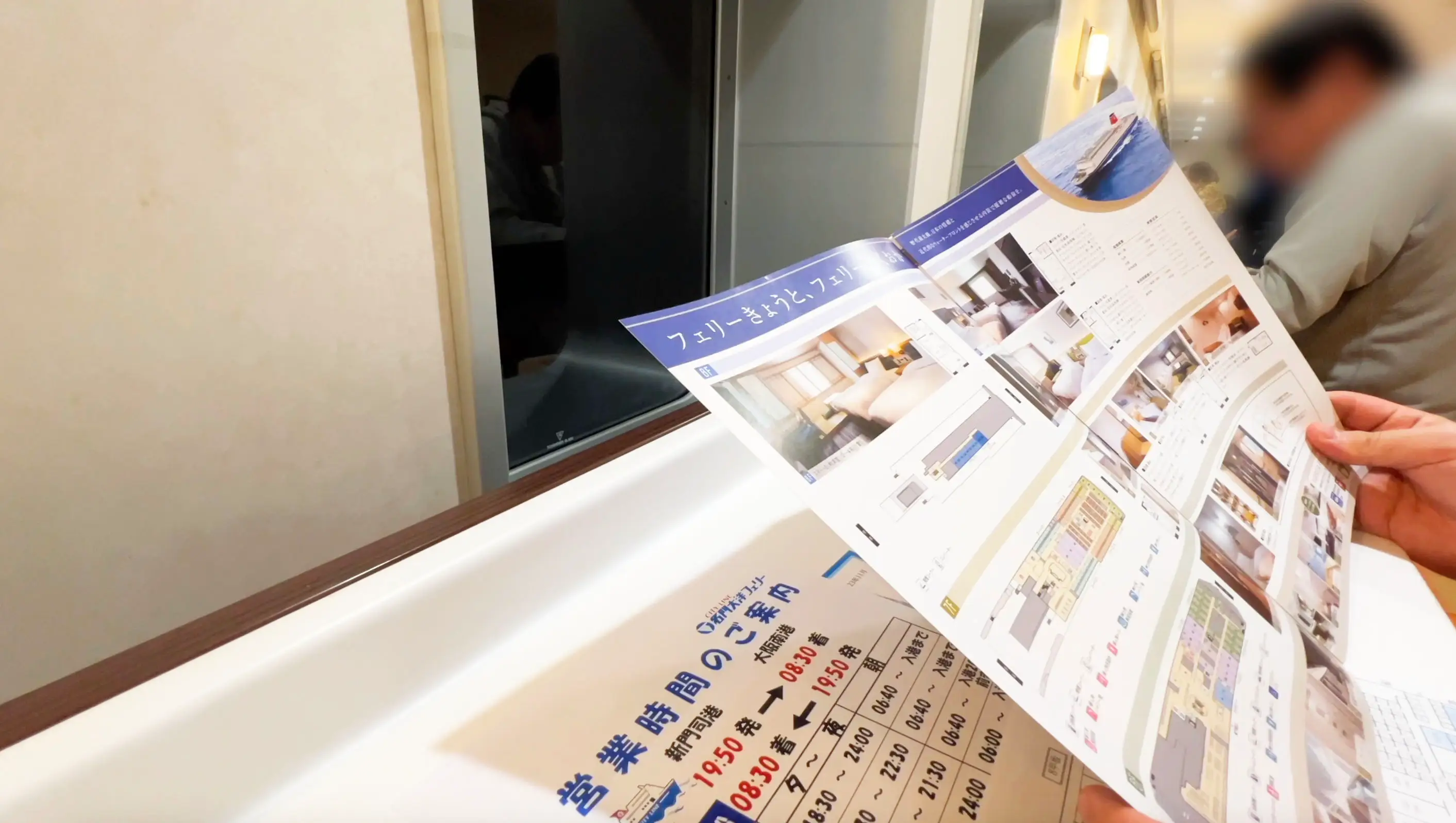 名门大洋渡轮京都船内的长廊中有人坐着阅读小册子