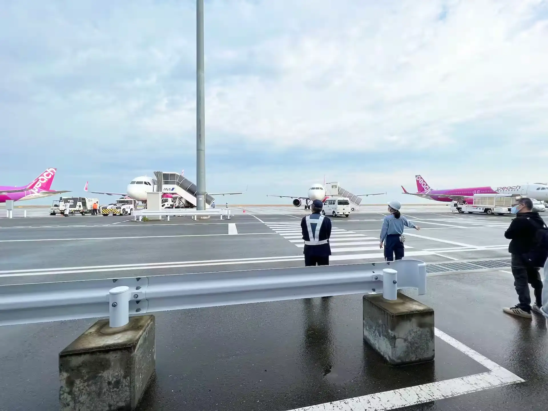 関西空港の滑走路に停まっているピーチアビエーションの機体とゲートを結ぶ通路で待機している様子