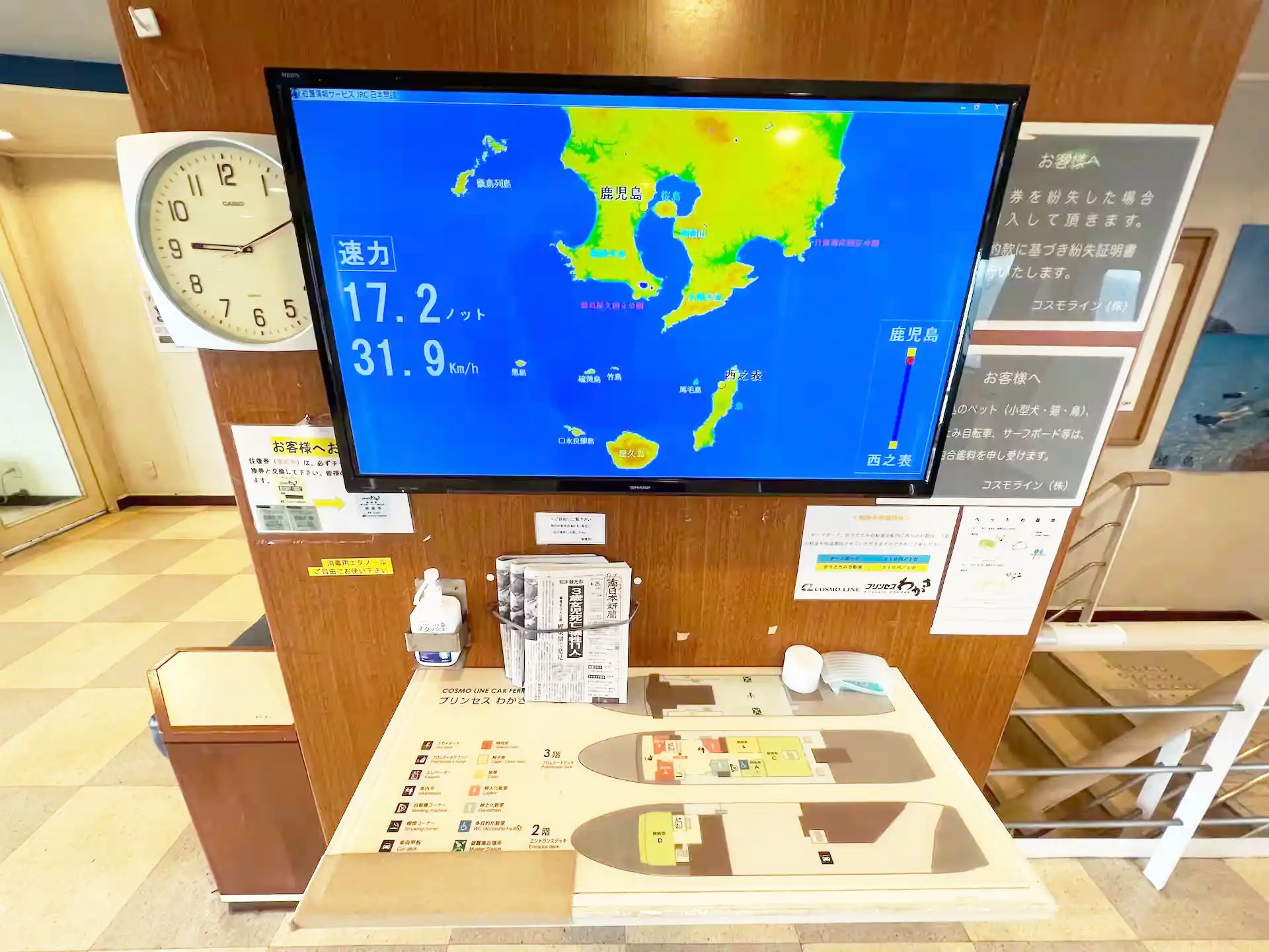 コスモラインのプリンセスわかさ船内の現在地が確認できるモニターと新聞と掛け時計